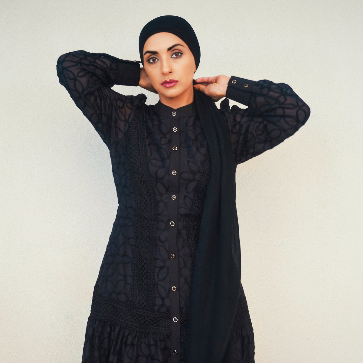 Woman wearing the Celeste Bloom Lace Midi Dress in black, featuring delicate lace, embroidered details and a modest feminine silhouette.