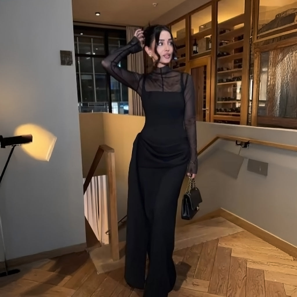 Women's black high-neck maxi dress with long sheer mesh sleeves, asymmetric draped waist detail.